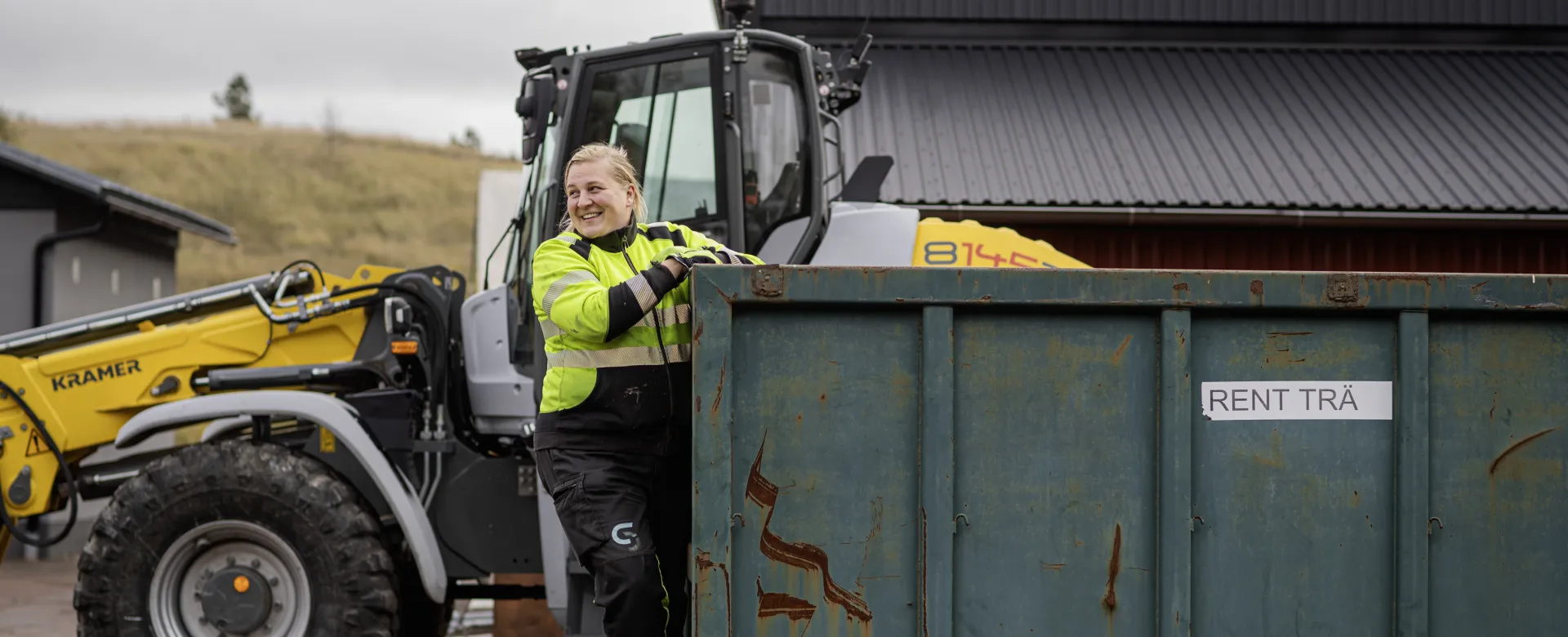 Kvinnlig anställd klättrar på container vid Svinryggens kretsloppsanläggning på Åland.