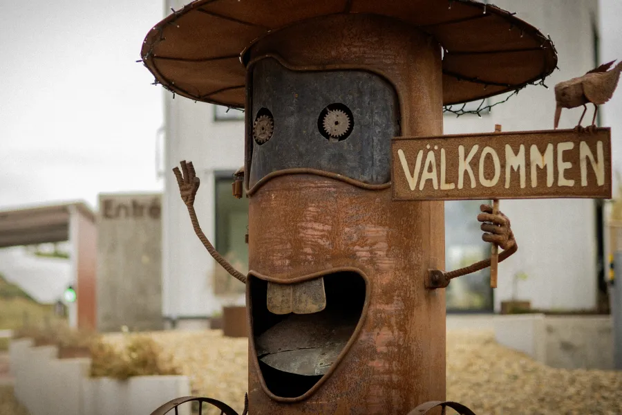 Glad skrotskulptur med välkomstskylt vid Svinryggens kretsloppsanläggning på Åland.