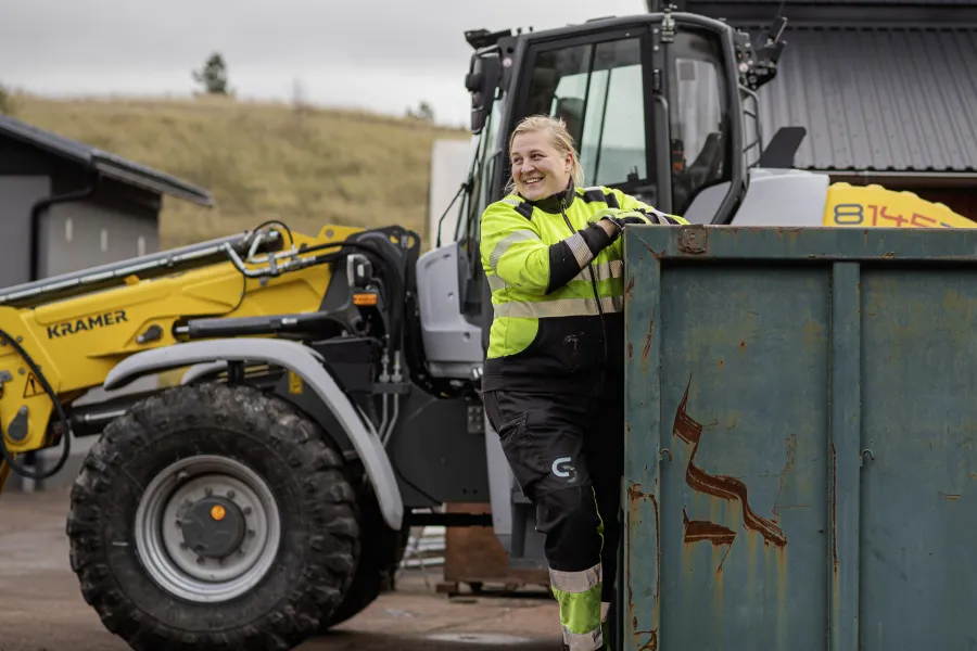 Kvinnlig anställd klättrar på container vid Svinryggens kretsloppsanläggning på Åland.